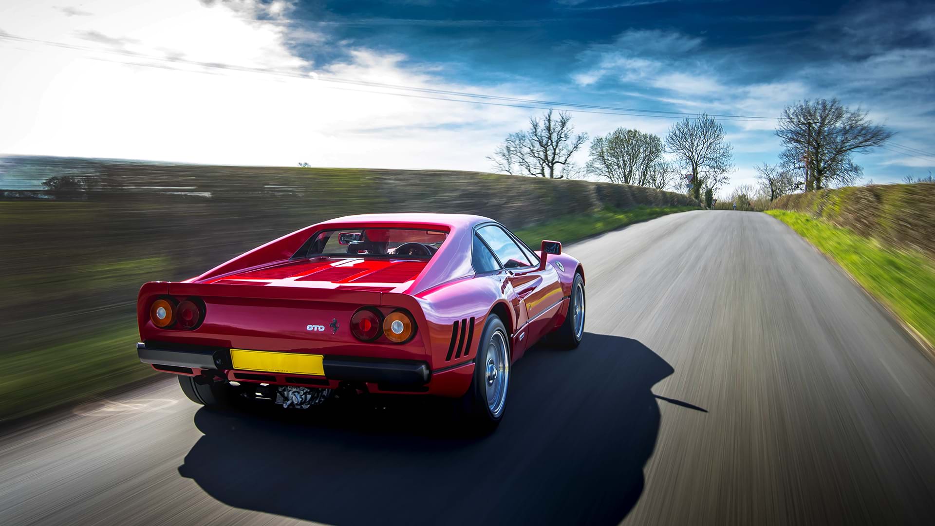 Rouge classique Ferrari 288 GTO dévalant à toute vitesse une route de campagne pittoresque. 